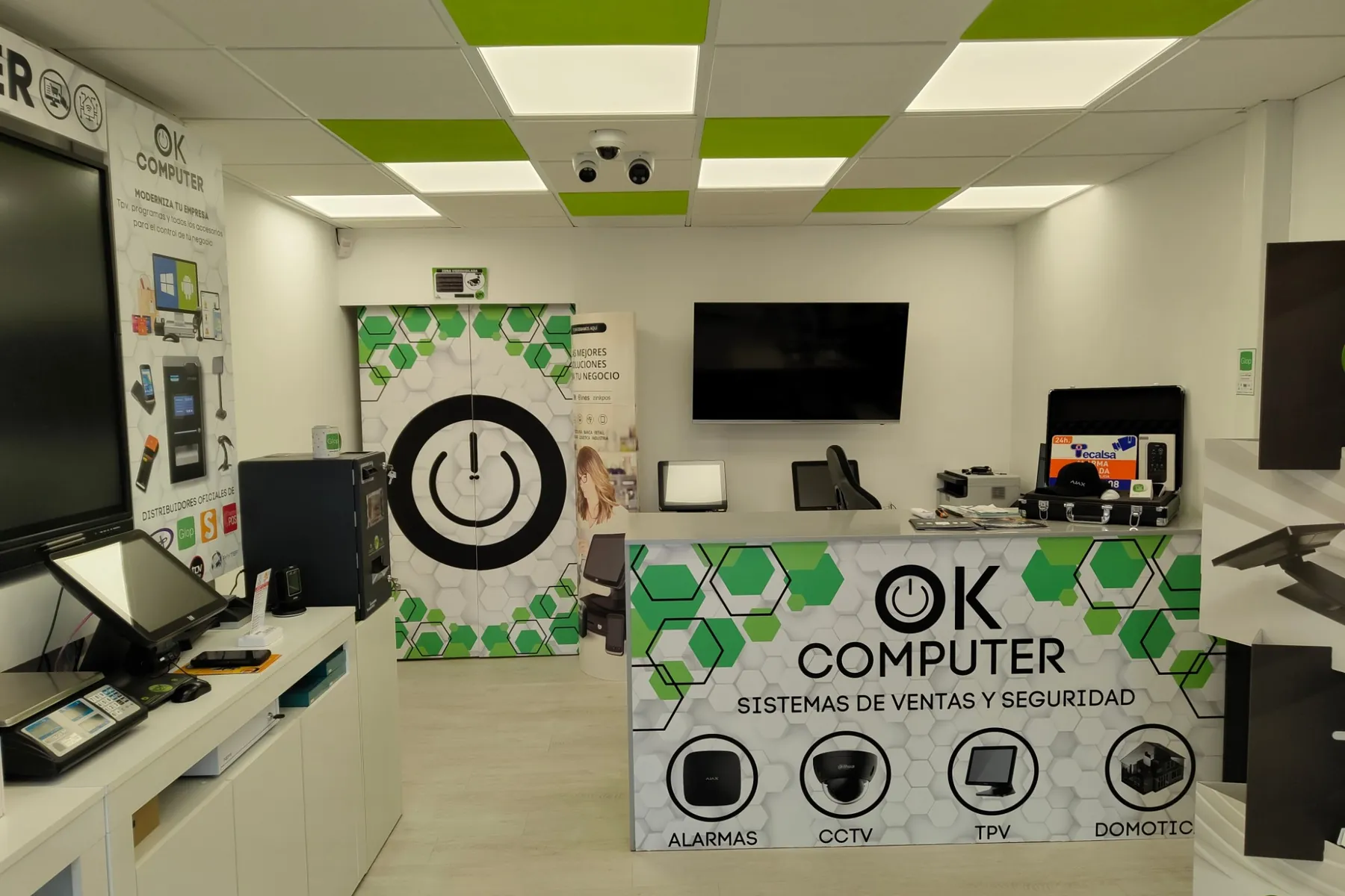 Interior de la tienda de OK Computer en Armeñime: mostrador con el logo, TPV a la izquierda y cámaras en el techo